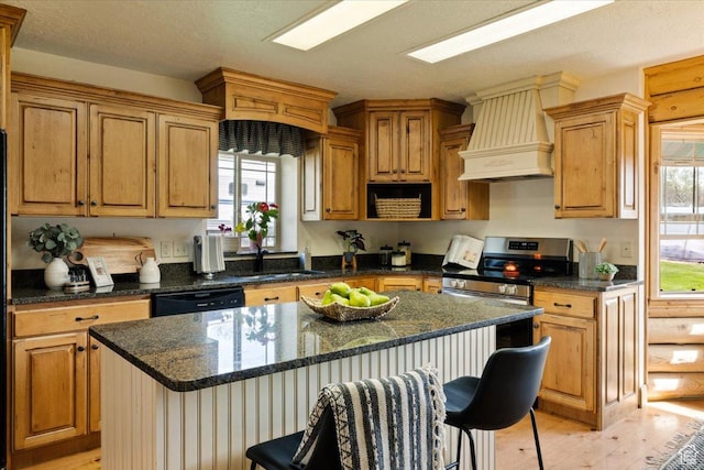 kitchen featuring a center island, black dishwasher, light wood finished floors, a sink, and premium range hood