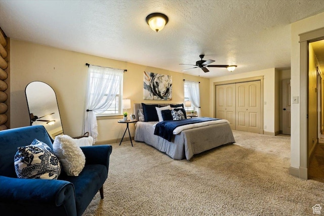 carpeted bedroom with baseboards, a closet, ceiling fan, and a textured ceiling