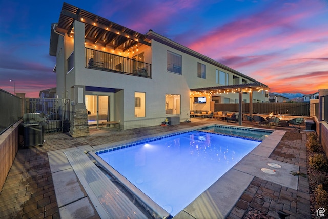 pool at dusk with a grill, a patio, a fenced backyard, and a pool with connected hot tub