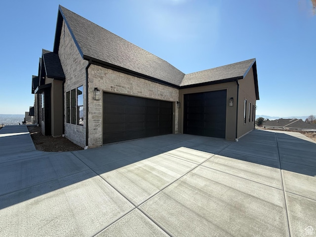 view of side of property with a garage, driveway, and stone siding
