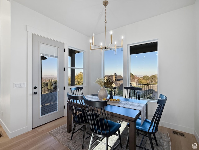 dining space featuring plenty of natural light, a notable chandelier, visible vents, and light wood-style flooring
