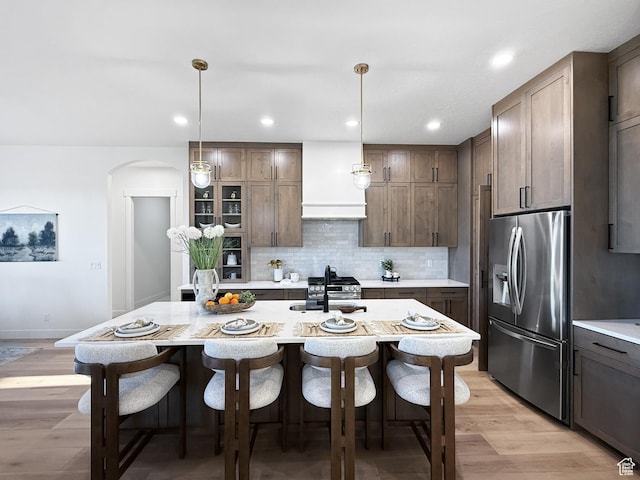 kitchen with arched walkways, appliances with stainless steel finishes, light countertops, and a breakfast bar