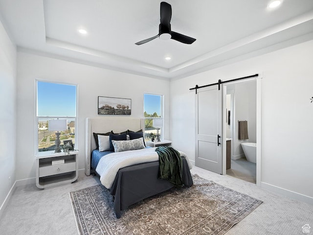 bedroom featuring baseboards, a barn door, a tray ceiling, recessed lighting, and light colored carpet