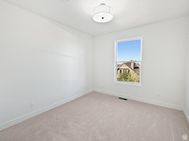 unfurnished room with light carpet, visible vents, and baseboards