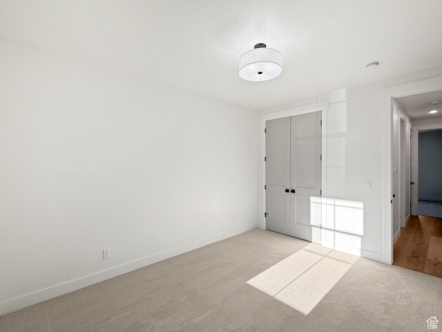 unfurnished room featuring baseboards and light carpet