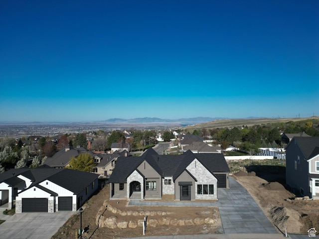 view of front of house with concrete driveway, a residential view, a mountain view, and an attached garage