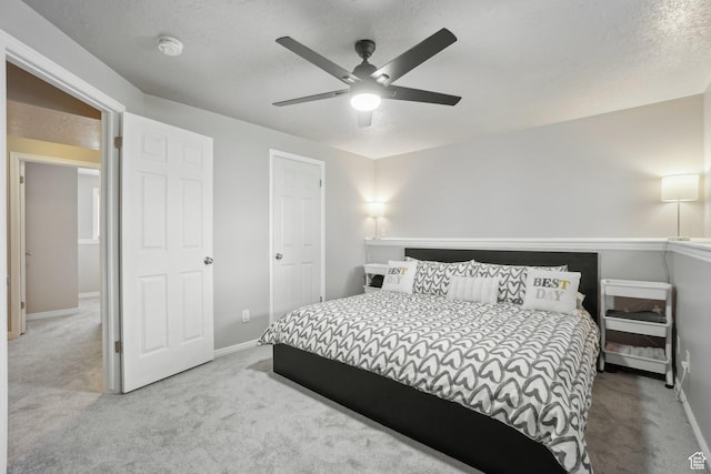 carpeted bedroom featuring baseboards, a ceiling fan, and a textured ceiling