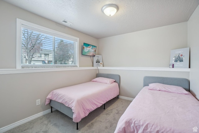 bedroom with visible vents, carpet, and a textured ceiling