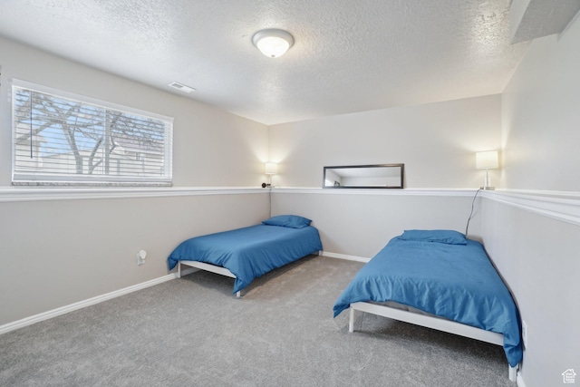 bedroom featuring baseboards, carpet flooring, a textured ceiling, and visible vents