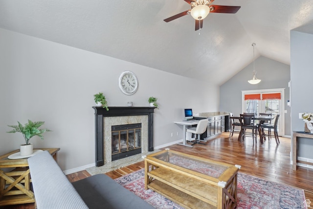 living room with ceiling fan, vaulted ceiling, wood finished floors, and a tile fireplace