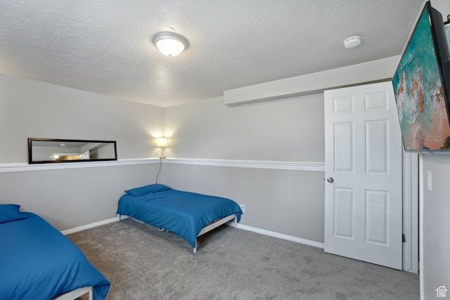 carpeted bedroom featuring a textured ceiling and baseboards