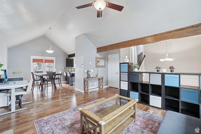 living area featuring lofted ceiling, wood finished floors, and ceiling fan with notable chandelier