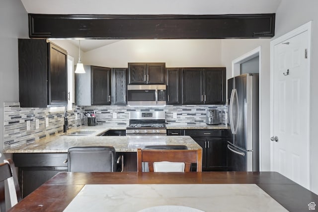 kitchen featuring backsplash, hanging light fixtures, stainless steel appliances, and a sink