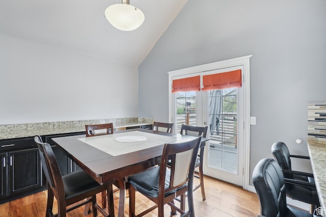 dining space featuring high vaulted ceiling and light wood finished floors