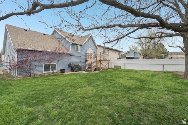 rear view of house featuring fence, a yard, and stairway