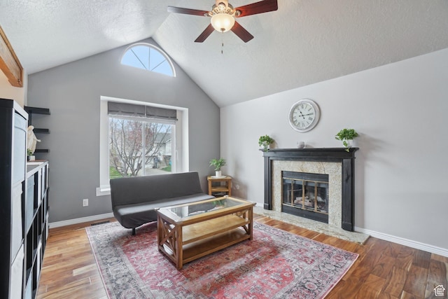 living area featuring a ceiling fan, a textured ceiling, plenty of natural light, a fireplace, and lofted ceiling