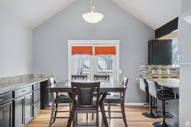 dining area with high vaulted ceiling, light wood-type flooring, and baseboards