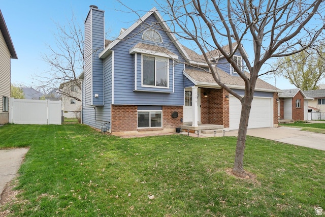 tri-level home with a chimney, fence, concrete driveway, brick siding, and a front yard