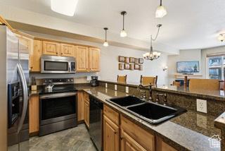 2669 Canyons Resort Dr Unit 207, Park City, UT 84098 - kitchen with hanging light fixtures, a notable chandelier, a sink, dark countertops, and stainless steel appliances