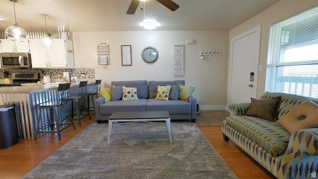 living room featuring wood finished floors, baseboards, and a ceiling fan