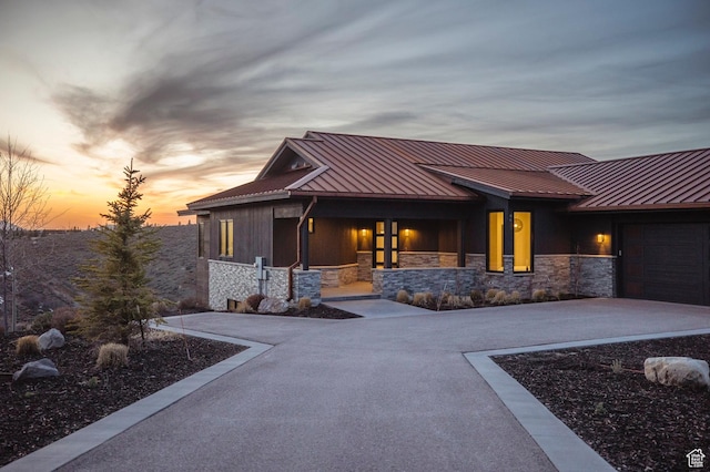 6633 Golden Bear Loop W, Park City, UT 84098 - back of house at dusk featuring concrete driveway, a standing seam roof, stone siding, and a garage