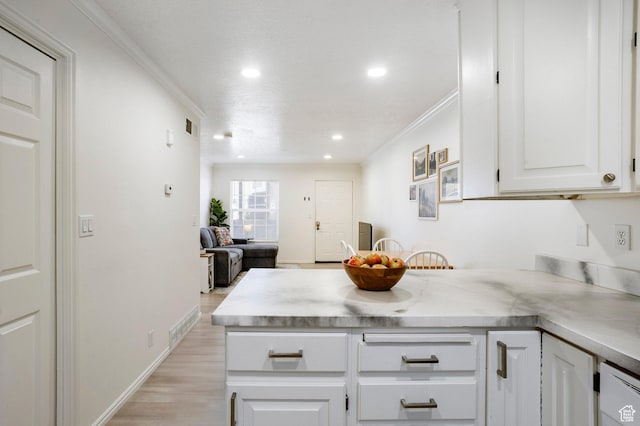 kitchen featuring a peninsula, light wood-style flooring, light countertops, crown molding, and white cabinets