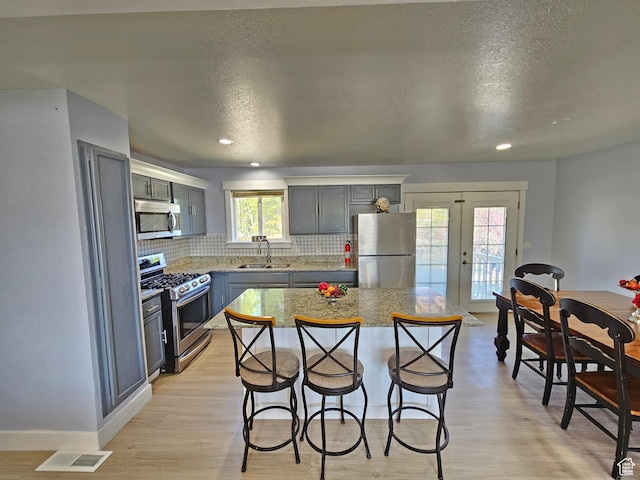3500 W 6875 S, West Jordan, UT 84084 - kitchen featuring appliances with stainless steel finishes, a breakfast bar area, decorative backsplash, french doors, and a sink