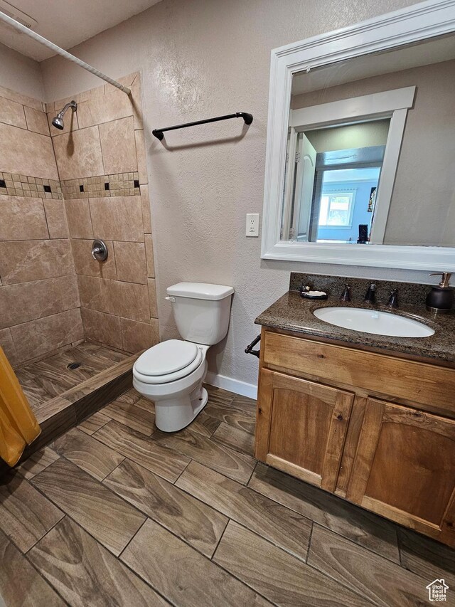 3500 W 6875 S, West Jordan, UT 84084 - bathroom featuring toilet, a tile shower, vanity, a textured wall, and baseboards
