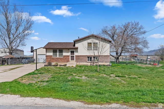 tri-level home with brick siding, an attached garage, fence, and driveway
