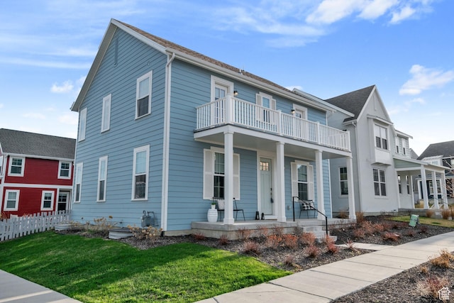 view of front of home with a balcony, a front lawn, and covered porch