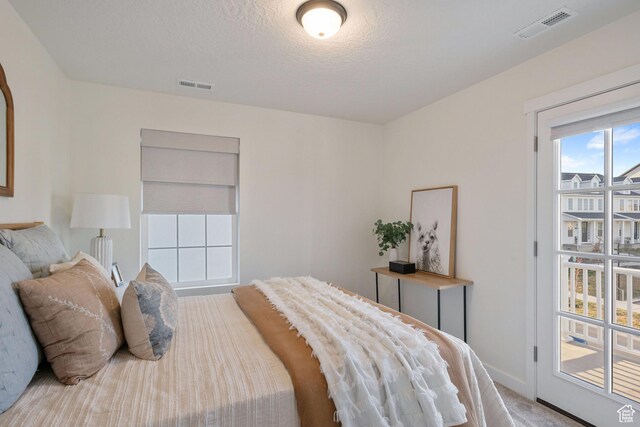 bedroom with a textured ceiling, light colored carpet, baseboards, and visible vents