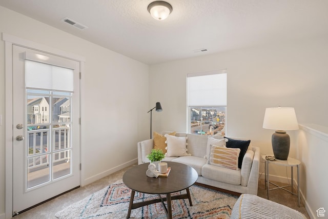 living area featuring baseboards, visible vents, and carpet floors
