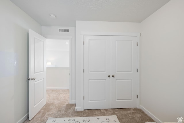 unfurnished bedroom featuring light carpet, a closet, baseboards, and visible vents