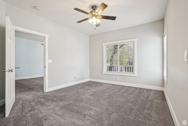 carpeted spare room featuring baseboards and a ceiling fan