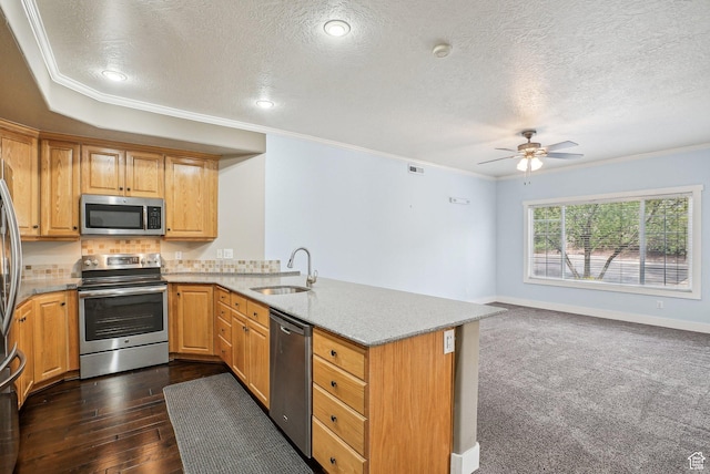 kitchen with a sink, a peninsula, a textured ceiling, light stone countertops, and stainless steel appliances