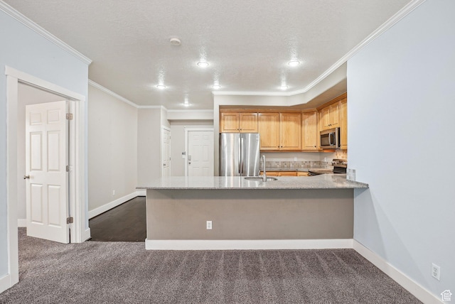 kitchen featuring a sink, dark carpet, ornamental molding, a peninsula, and stainless steel appliances