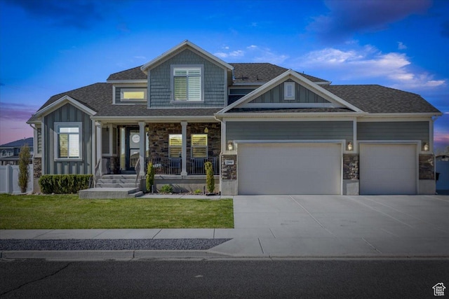 craftsman-style home featuring an attached garage, driveway, stone siding, and a porch