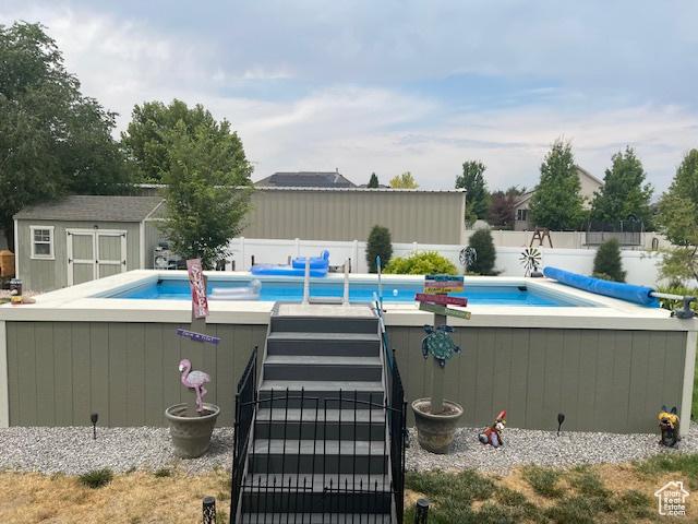 view of swimming pool featuring an outbuilding, a fenced backyard, and a storage unit