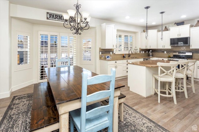 dining space with a chandelier, light wood-type flooring, baseboards, and recessed lighting