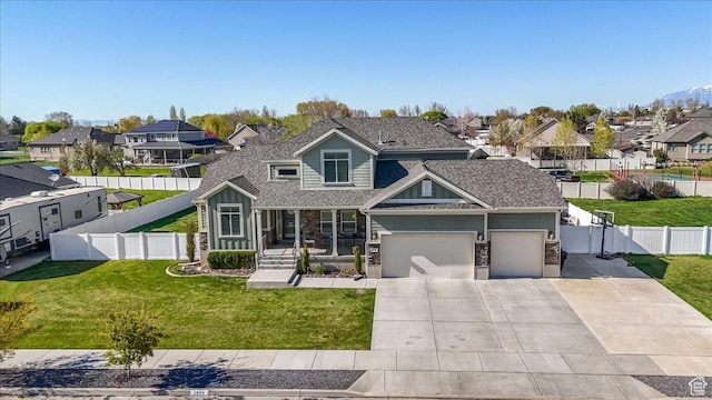 view of front of house featuring concrete driveway, a residential view, fence, and a front lawn