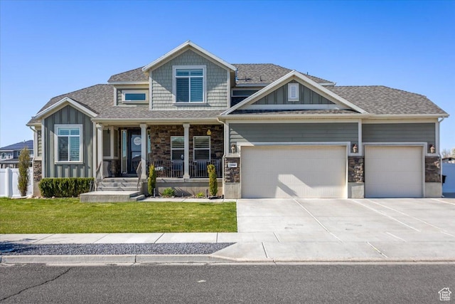 view of front facade featuring an attached garage, concrete driveway, stone siding, and covered porch