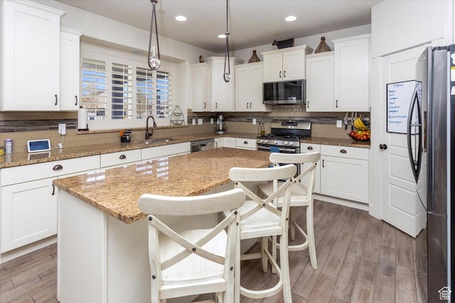 kitchen featuring white cabinetry, a center island, backsplash, stainless steel appliances, and a sink