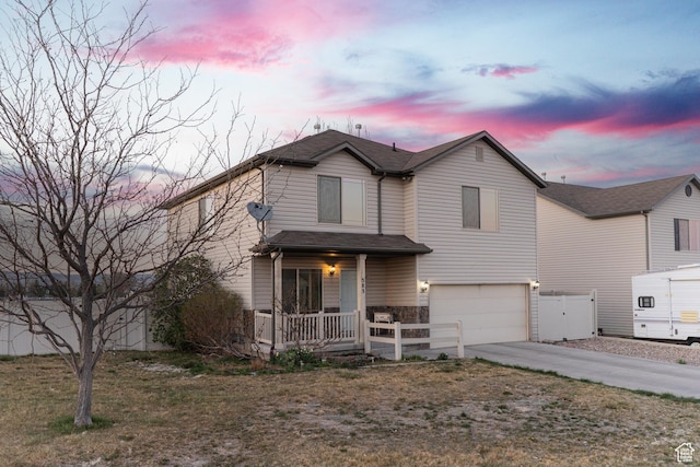 traditional home featuring a porch, an attached garage, and driveway