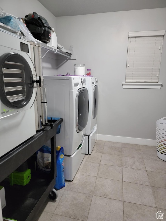 washroom featuring laundry area, light tile patterned floors, baseboards, and washer and clothes dryer
