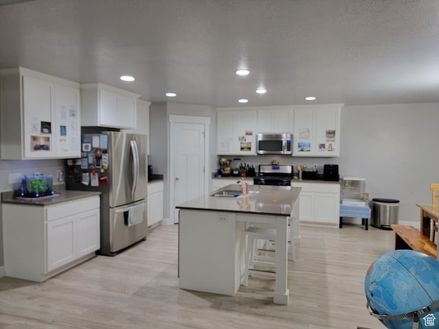 kitchen featuring recessed lighting, white cabinetry, light wood-style floors, stainless steel appliances, and a sink