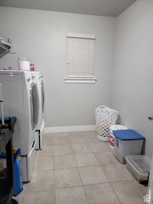 laundry area featuring laundry area, separate washer and dryer, light tile patterned flooring, and baseboards