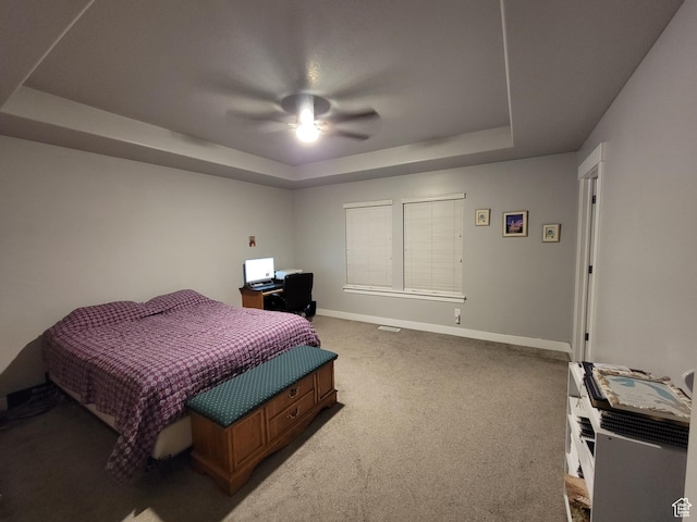 bedroom with carpet flooring, a tray ceiling, baseboards, and ceiling fan