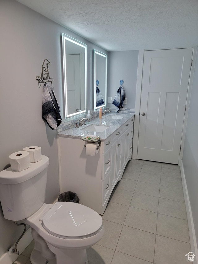 bathroom featuring tile patterned flooring, vanity, a textured ceiling, and toilet