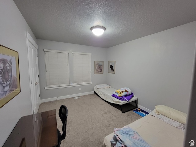 bedroom with a textured ceiling, baseboards, visible vents, and carpet floors