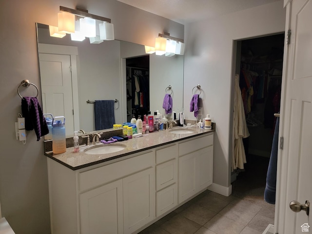 full bathroom with a sink, a spacious closet, tile patterned floors, and double vanity